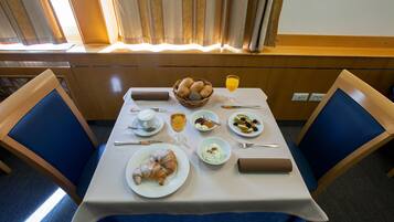 Una tavola imbandita per la colazione con croissant, frutta e un bicchiere di succo d'arancia.