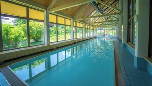 Una piscina interior larga con ventanas amplias y suelo de baldosas.