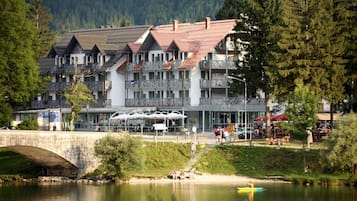 A multi-story hotel with balconies, a stone bridge, and a river.