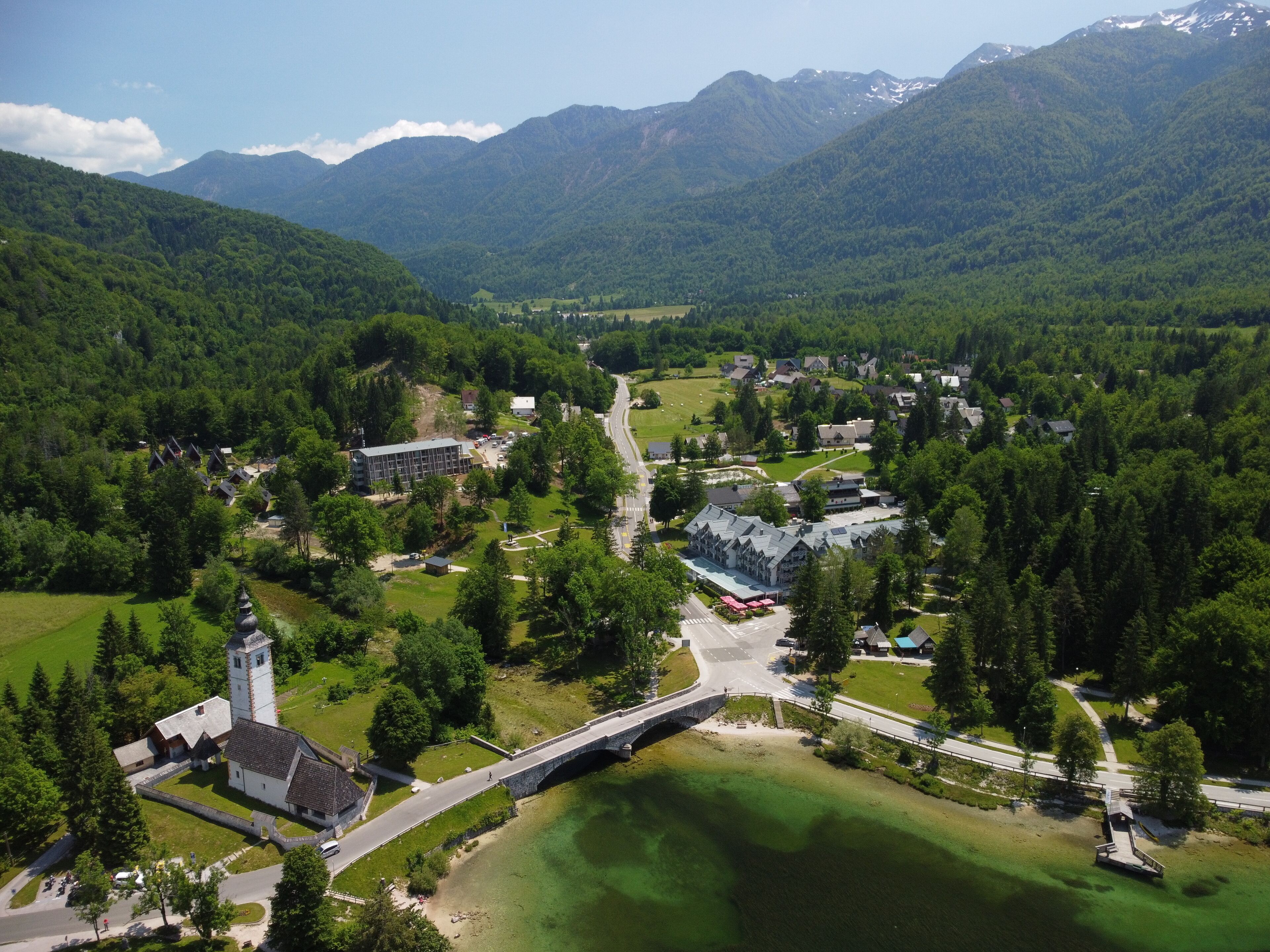 An aerial view of a small town with a prominent church, a bridge, and a lake.