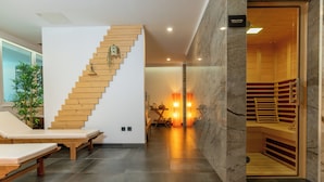 Un área de spa moderna con una escalera de madera, sillas de masaje y una sauna.
