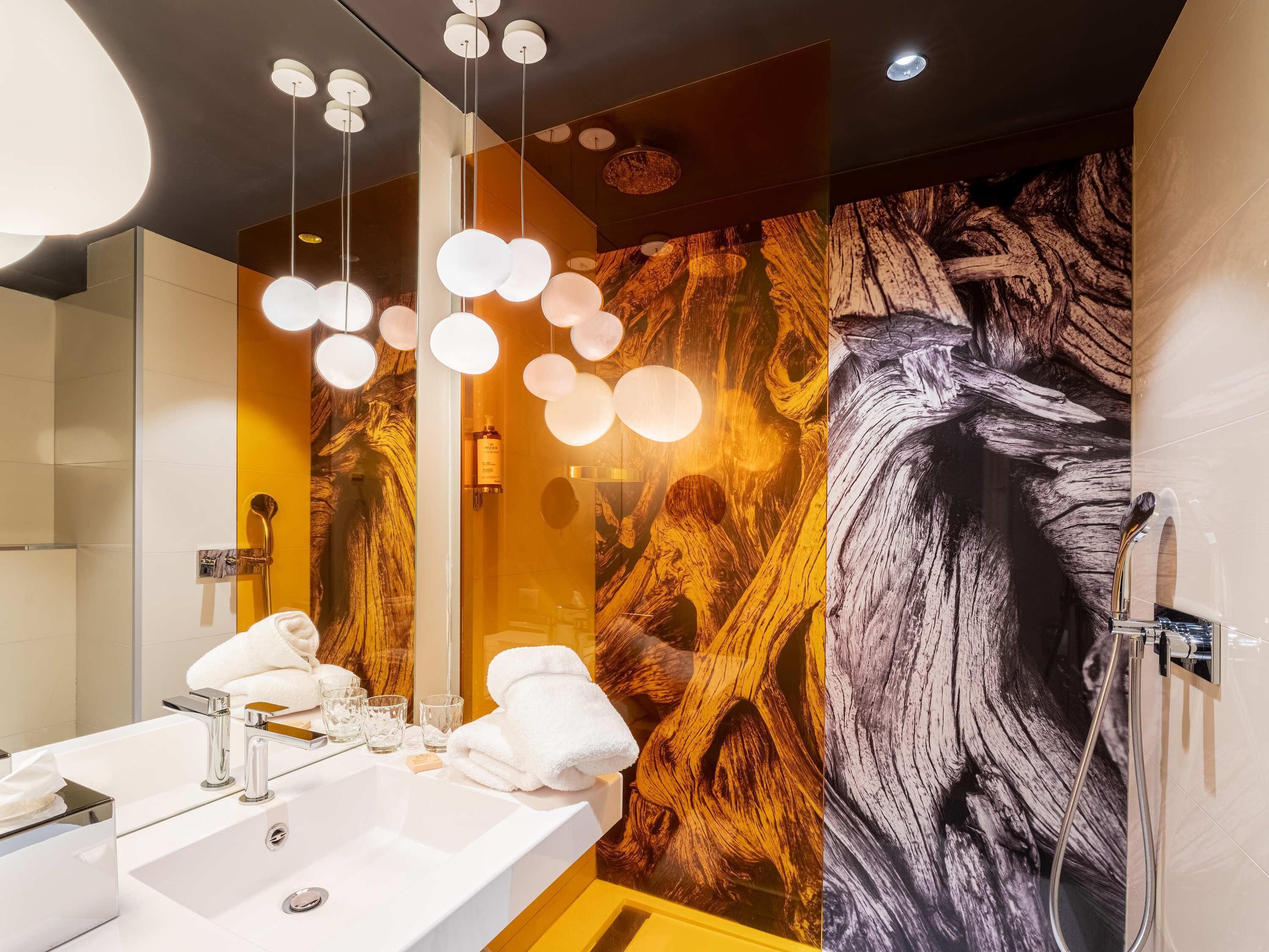 A modern bathroom with a large mirror, dual sinks, and a wooden wall mural.