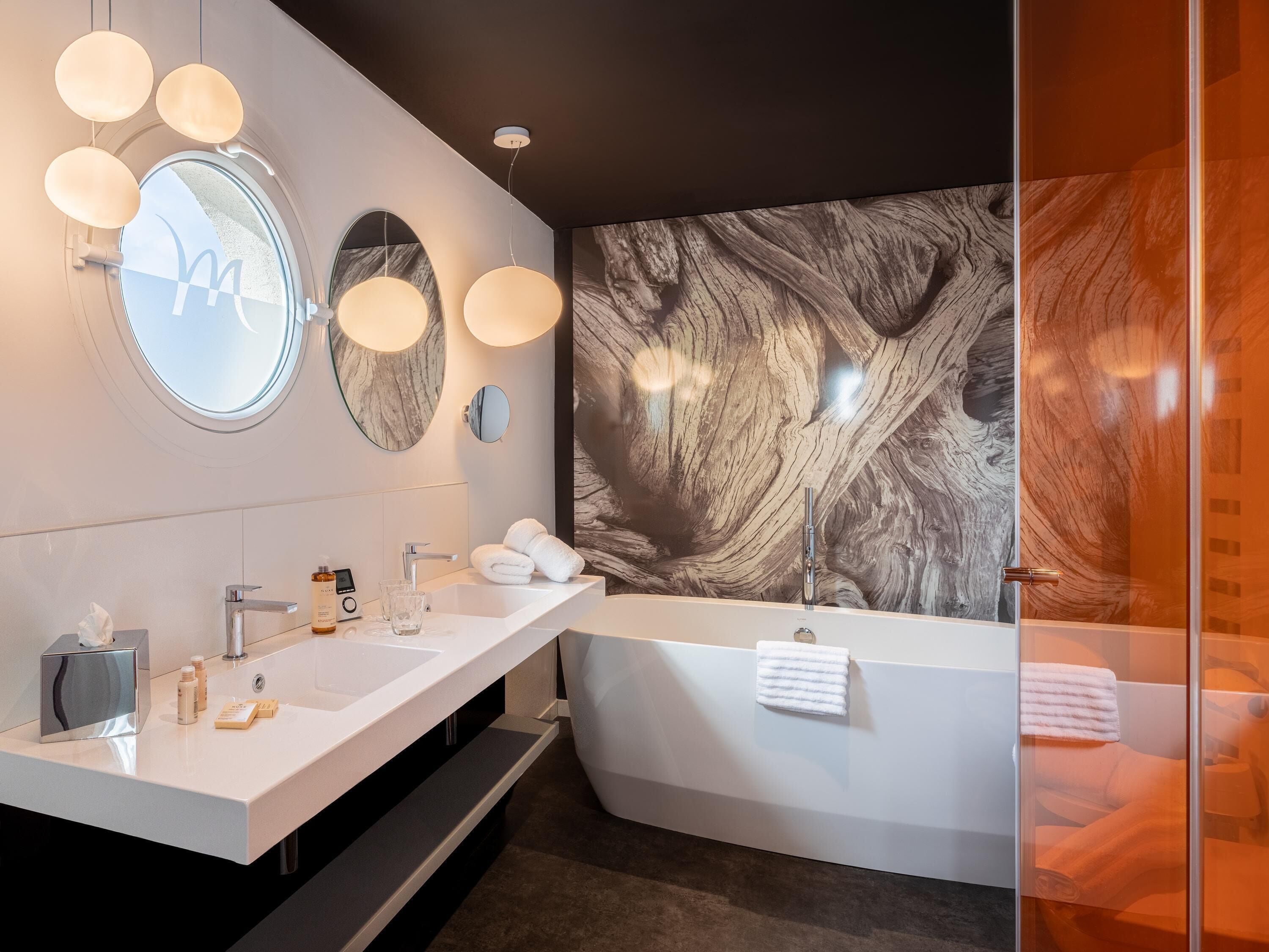 A modern bathroom with a double sink, a large mirror, and a wall-mounted light fixture.