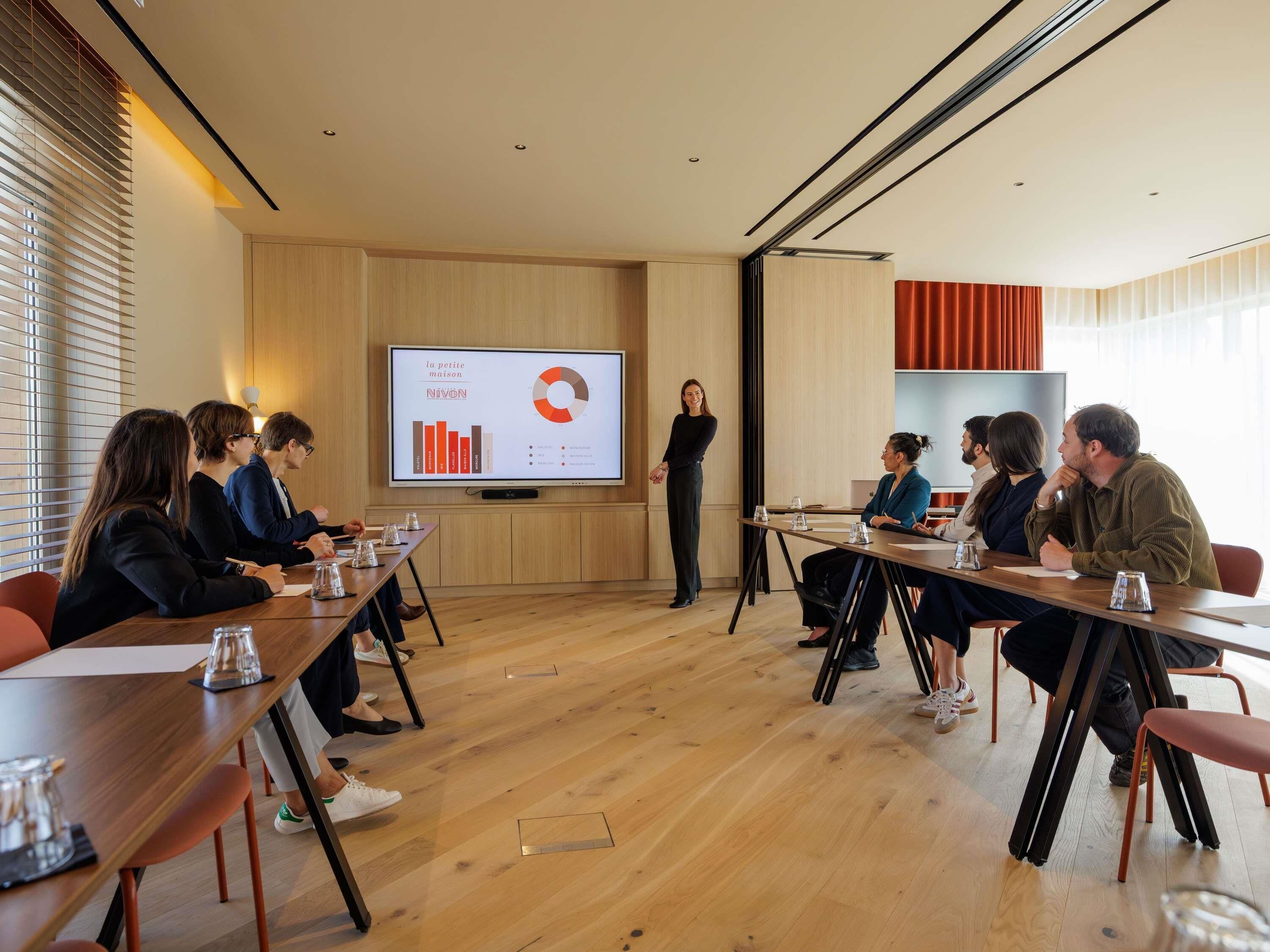 Un salón de conferencias con pantalla de presentación, suelos de madera y diseño moderno.