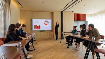 Un salón de conferencias con pantalla de presentación, suelos de madera y diseño moderno.