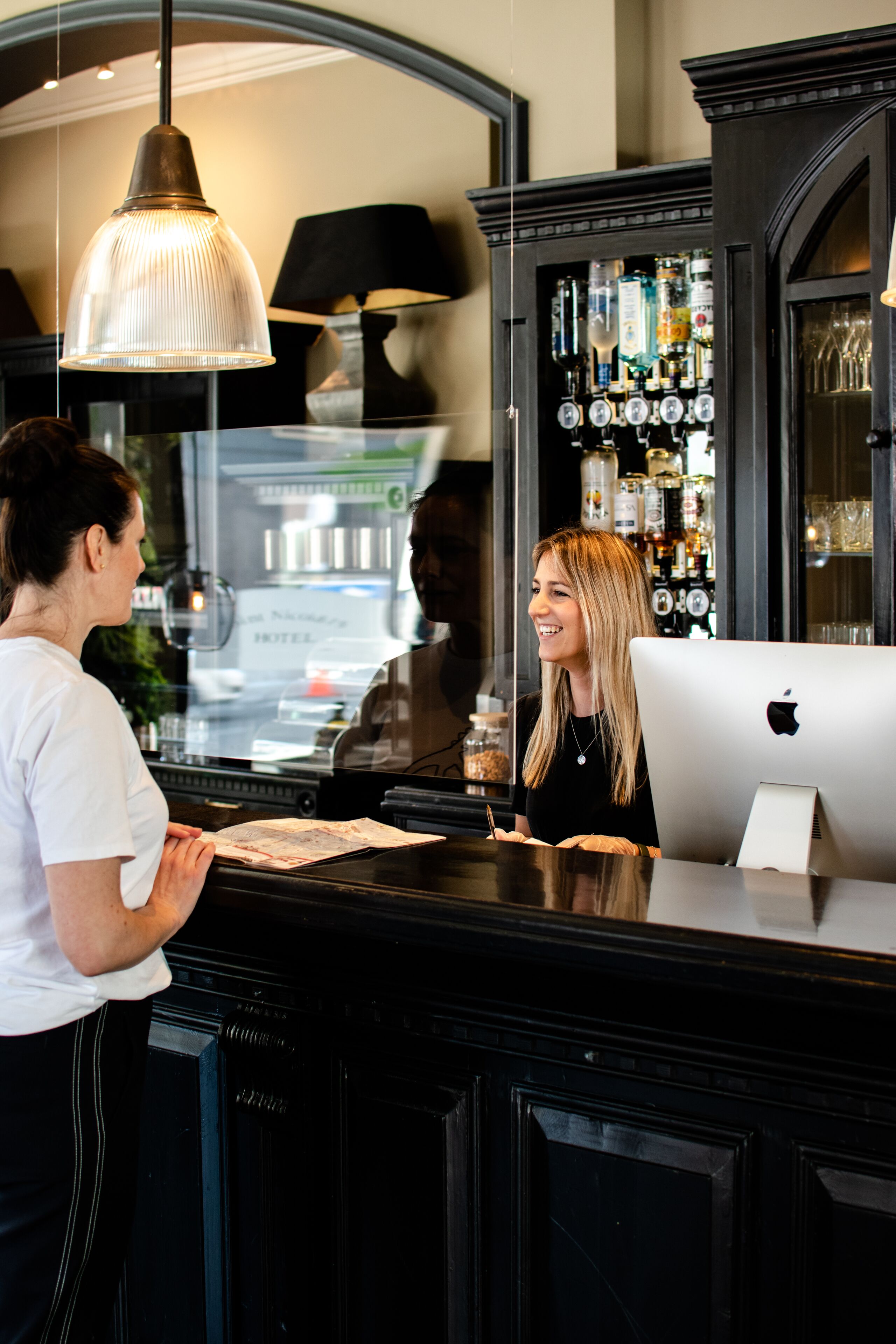 A bar area with a counter, a computer, and a display of liquor bottles.