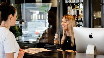 A bar area with a counter, a computer, and a display of liquor bottles.