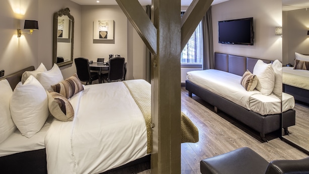 A hotel room with a large bed, a smaller bed, a desk, and a TV.