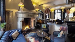 A lounge area with a fireplace, seating, and a large window.
