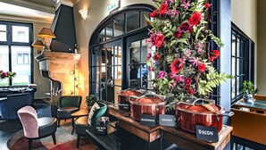 A restaurant with a black interior, copper pots labeled with dishes like scrambled eggs and bacon, and a large floral arrangement.