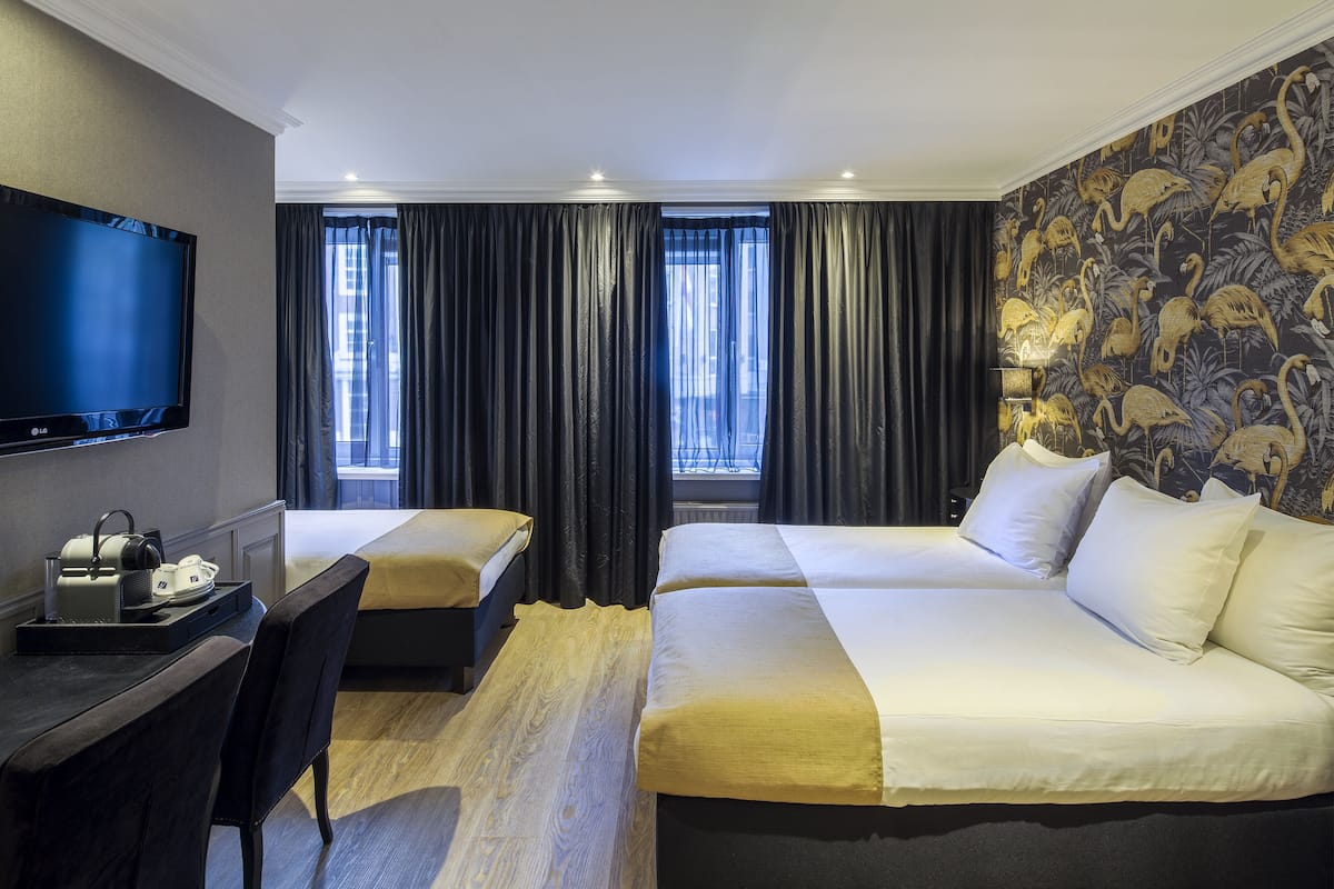 A hotel room with a bed, a desk, a TV, and a window with curtains.