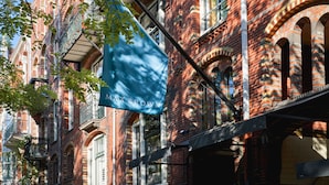 A red brick building with multiple windows and a blue awning. - Max Brown Hotel Museum Square, part of Sircle Collection (Amsterdam)