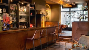 A bar area with stools, shelves of bottles and glasses, and a neon sign. - Max Brown Hotel Museum Square, part of Sircle Collection (Amsterdam)