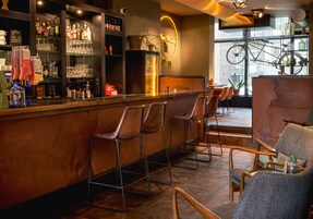 Eine Bar mit Hockern, Flaschen- und Glasregalen sowie einem Neonzeichen.