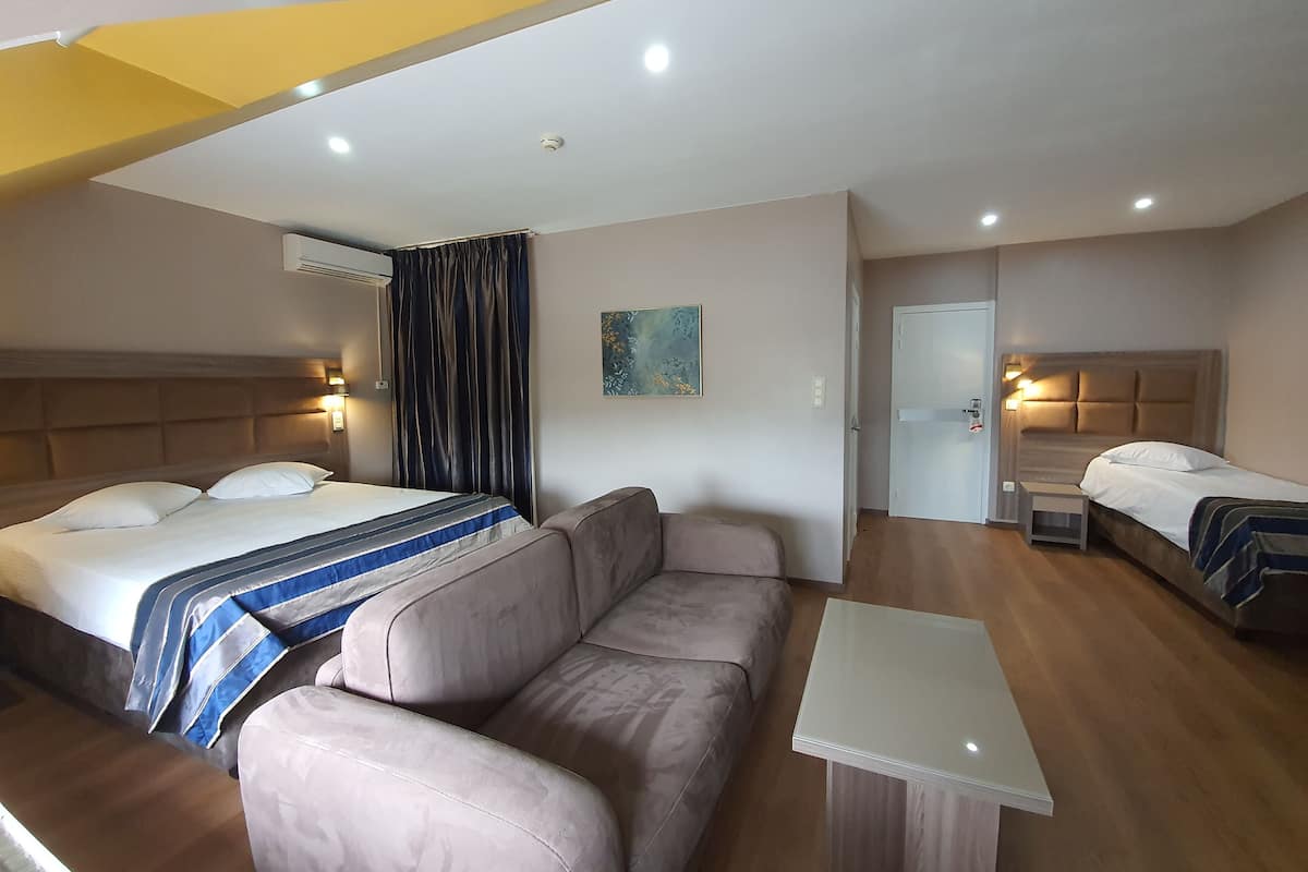 Una habitación de hotel con una cama, un sofá, una mesita y una puerta.