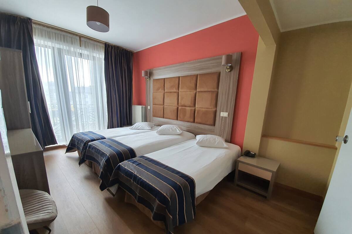 Habitación de hotel con dos camas, un escritorio y una silla.