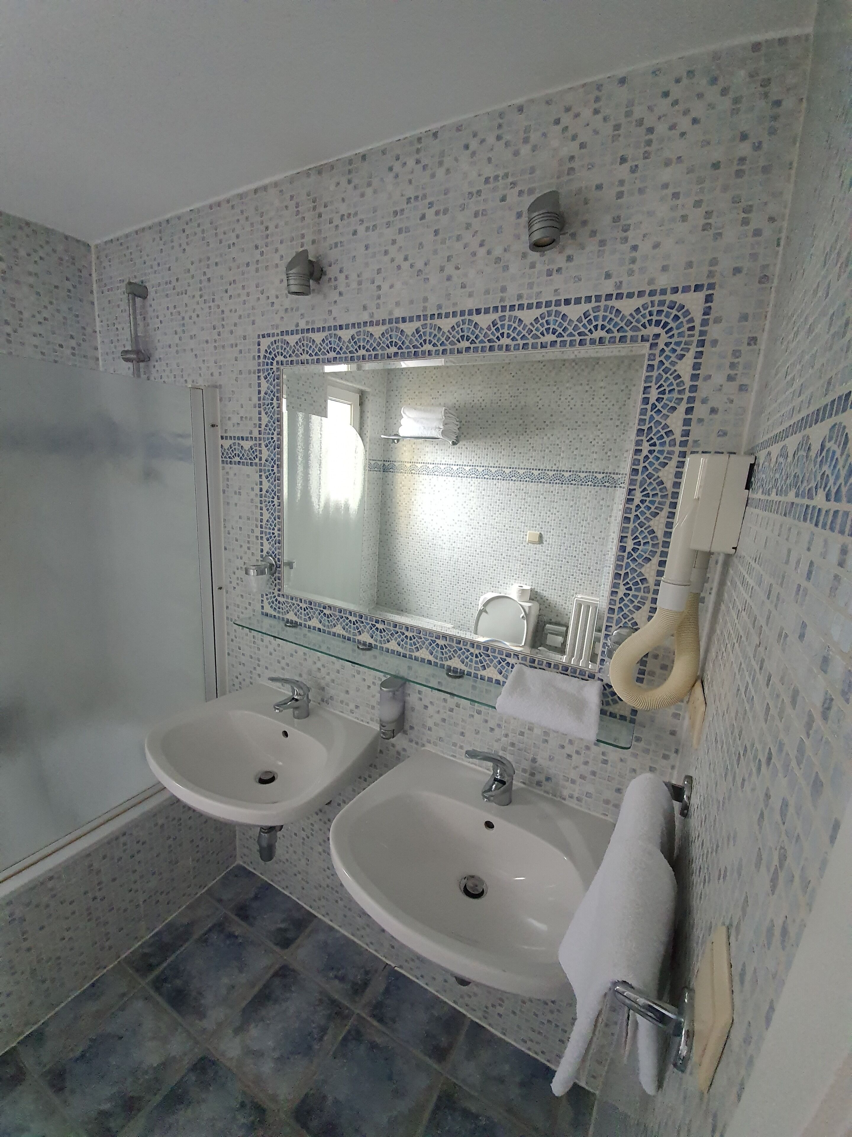 A bathroom with two sinks, a mirror, and a shower.