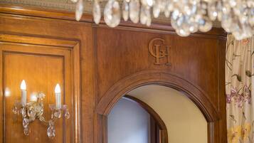 A wooden door with a carved 'H' and a chandelier with crystal details.