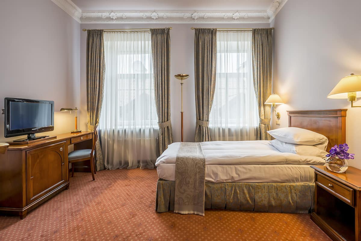 A hotel room with a bed, a desk, a television, and a lamp.