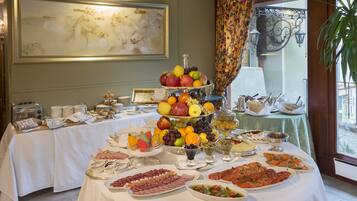 A buffet table with various food items and a large painting on the wall.