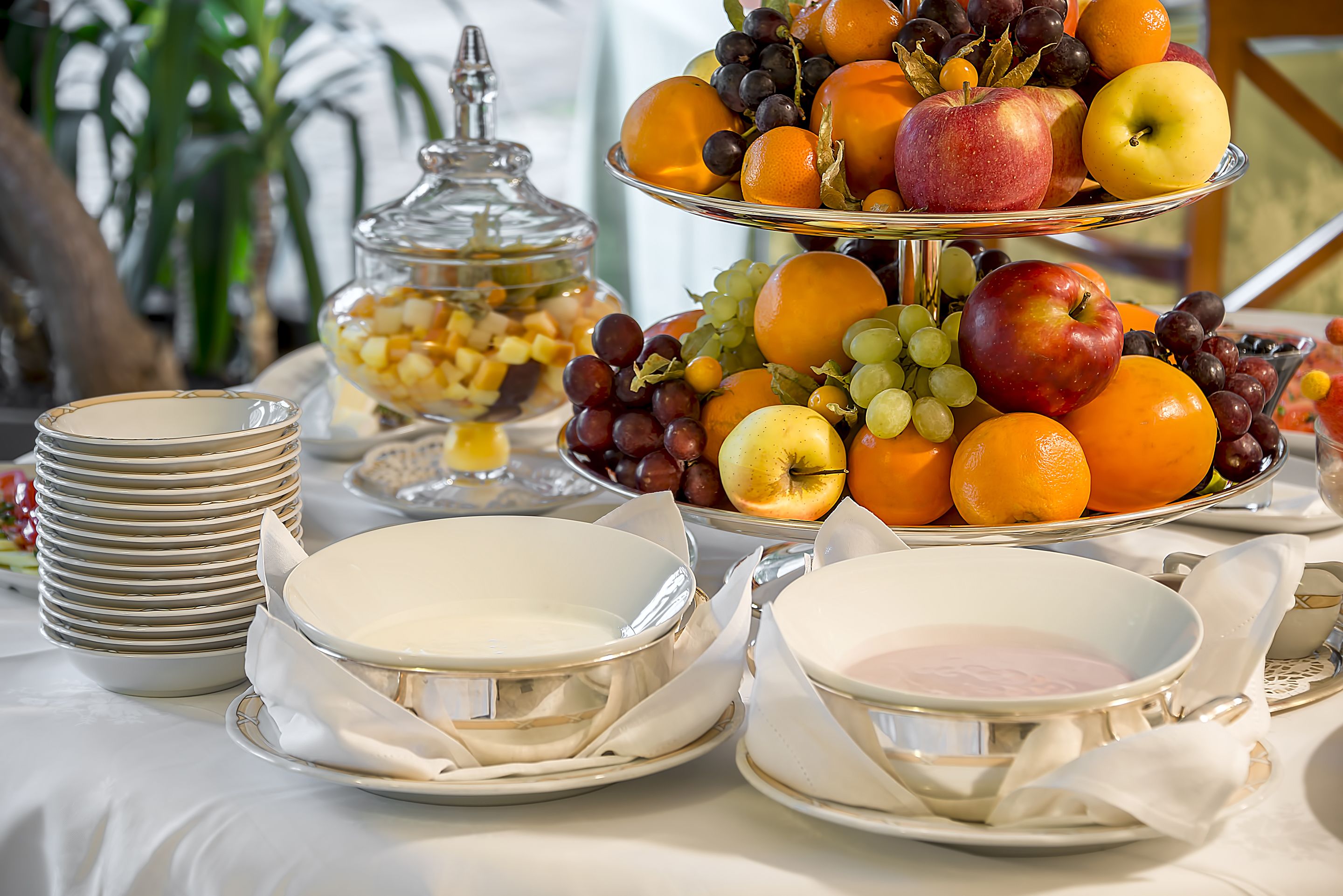 A table with a fruit display, plates, and a glass container.