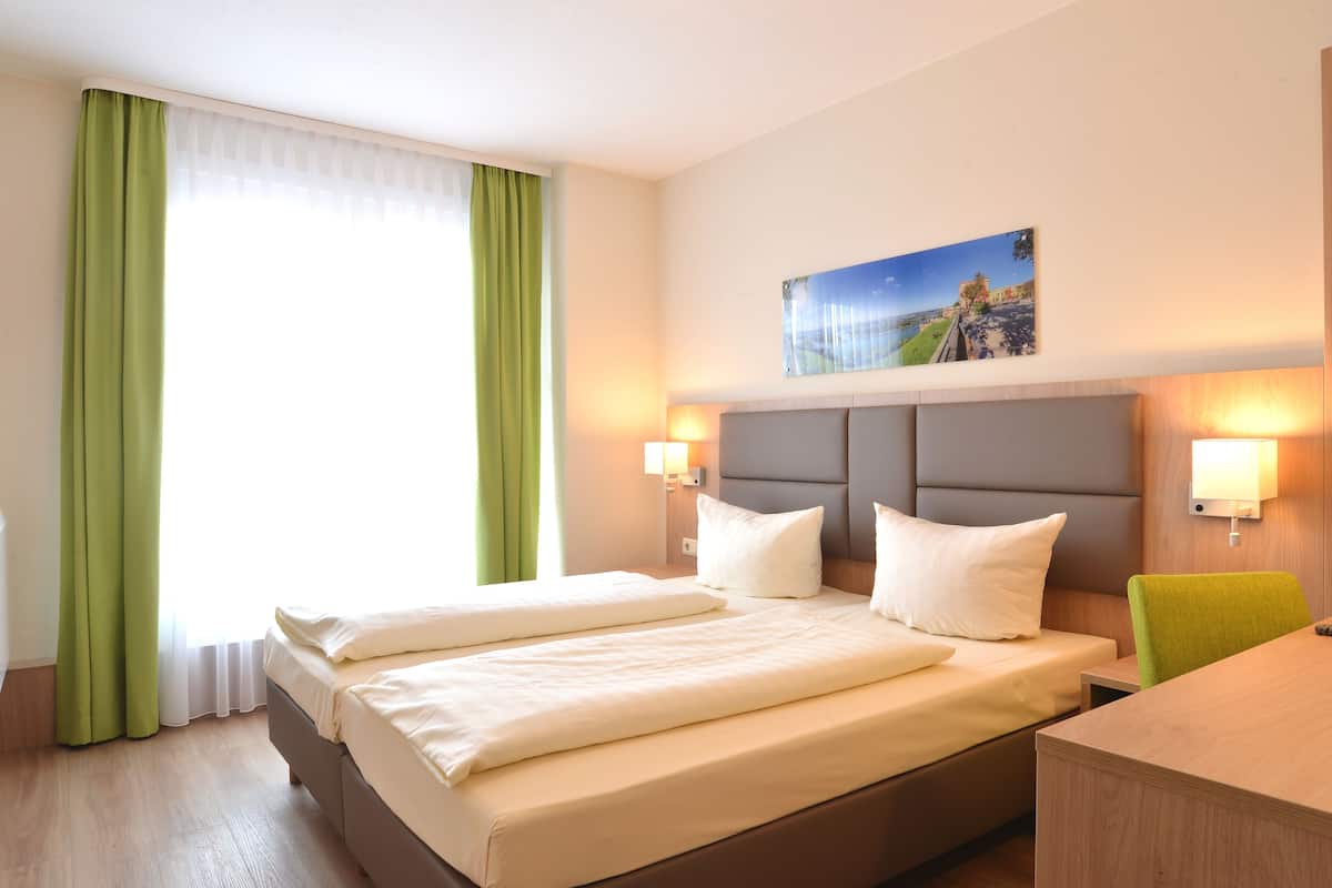 Une chambre d’hôtel avec un grand lit, deux tables de chevet, un bureau et une chaise.