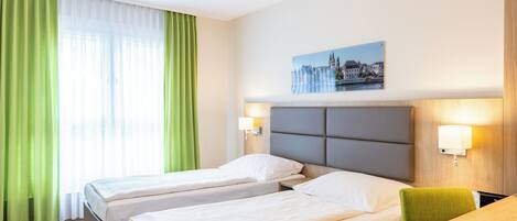 Habitación de hotel con dos camas, un escritorio, una silla y un cuadro en la pared.
