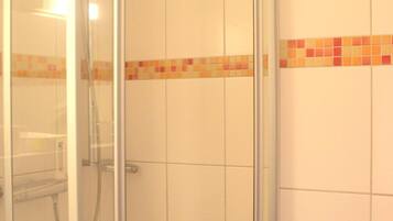 Un box de ducha con paredes de vidrio, pared con azulejos y un borde decorativo de azulejos.