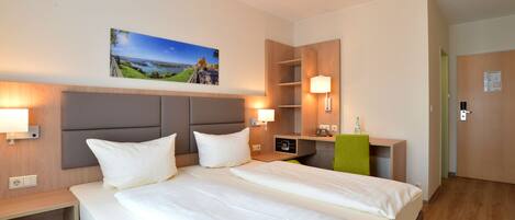 A hotel room with a large bed, bedside tables, a desk, and a mirror.