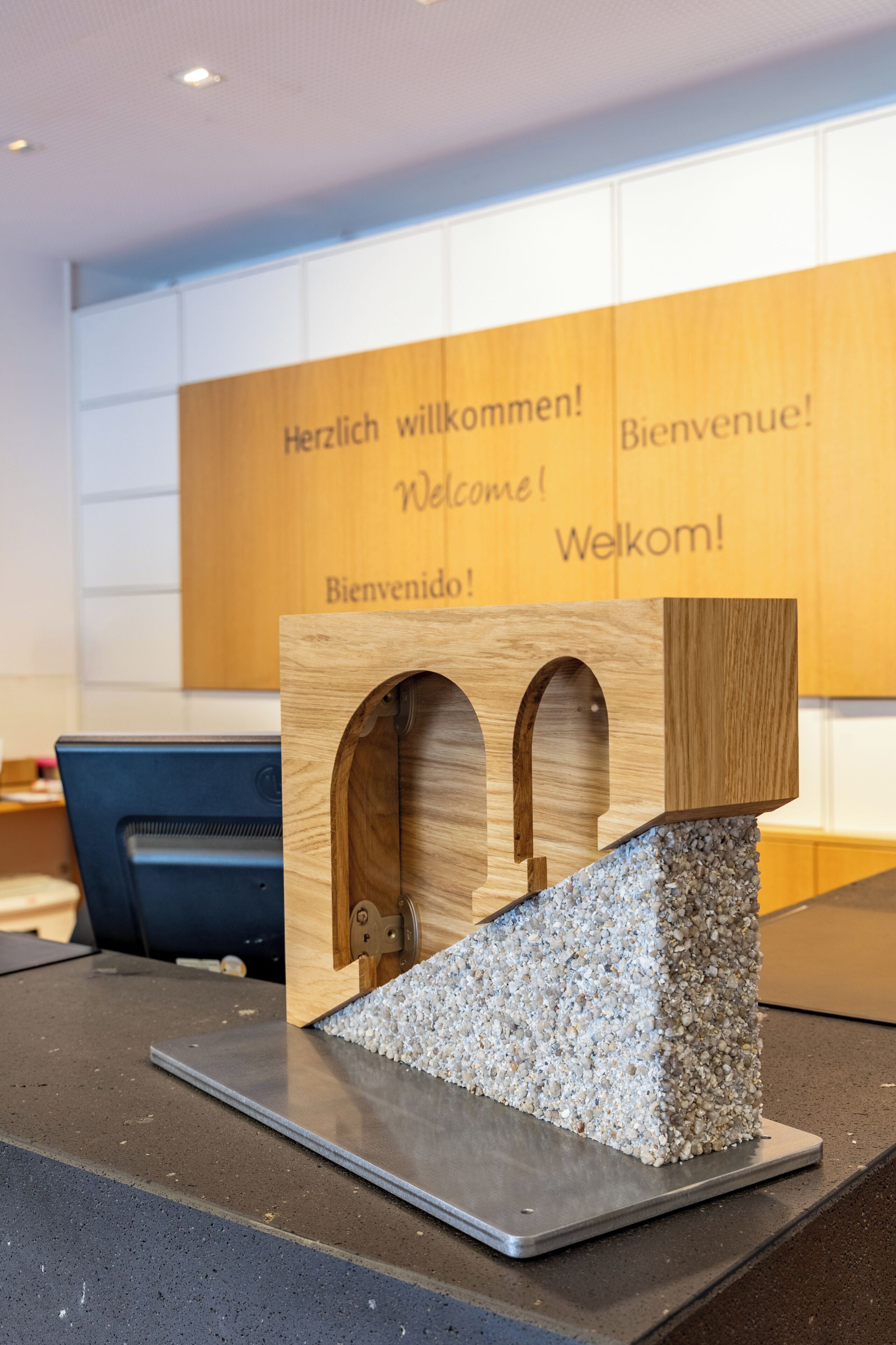 Un mostrador de recepción con una estructura de madera modelo que presenta carteles de bienvenida en varios idiomas.