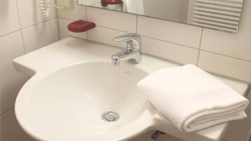 A white bathroom sink with a chrome faucet, a red soap dish, and a white towel on a white countertop.