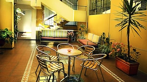 Un atrium à plusieurs niveaux, doté d’un escalier, d’un espace détente avec des chaises et une table, ainsi que de plantes en pot.