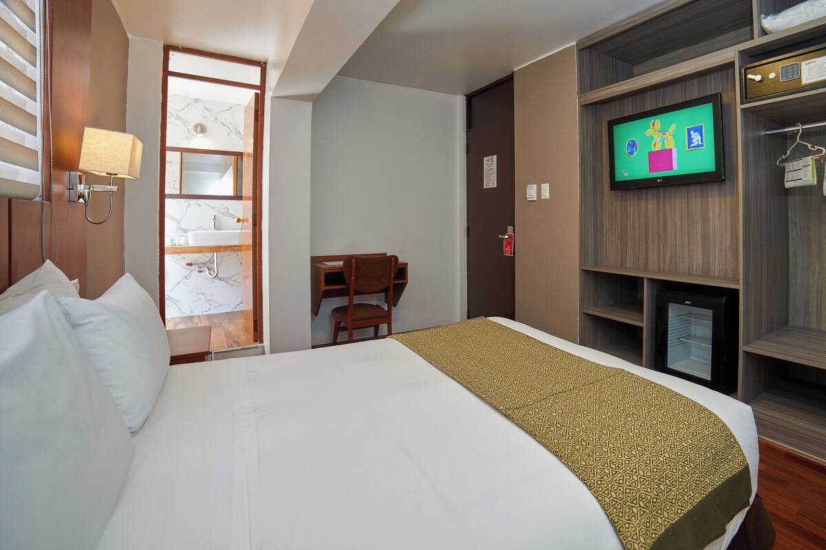 Ein Hotelzimmer mit Bett, Schreibtisch, Fernseher und Kleiderschrank.