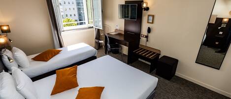 Une chambre d’hôtel avec deux lits, un bureau, une télévision et un miroir.