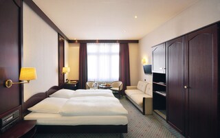 Una habitación de hotel con una cama doble, un sofá, un televisor, un escritorio y un armario.