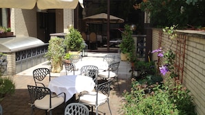 Une terrasse extérieure avec un mur en briques, un espace salon abrité et des plantes en pot.
