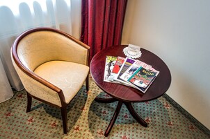 Una habitación con un sillón de madera y una pequeña mesa redonda con revistas.