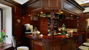 Un espace bar avec des lambris en bois, une machine à café et une variété de bouteilles et de verres.