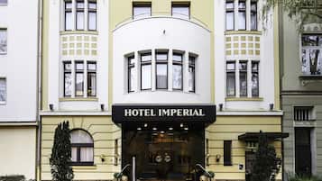 Un immeuble dont l’entrée est marquée par une enseigne indiquant « HÔTEL IMPÉRIAL ».
