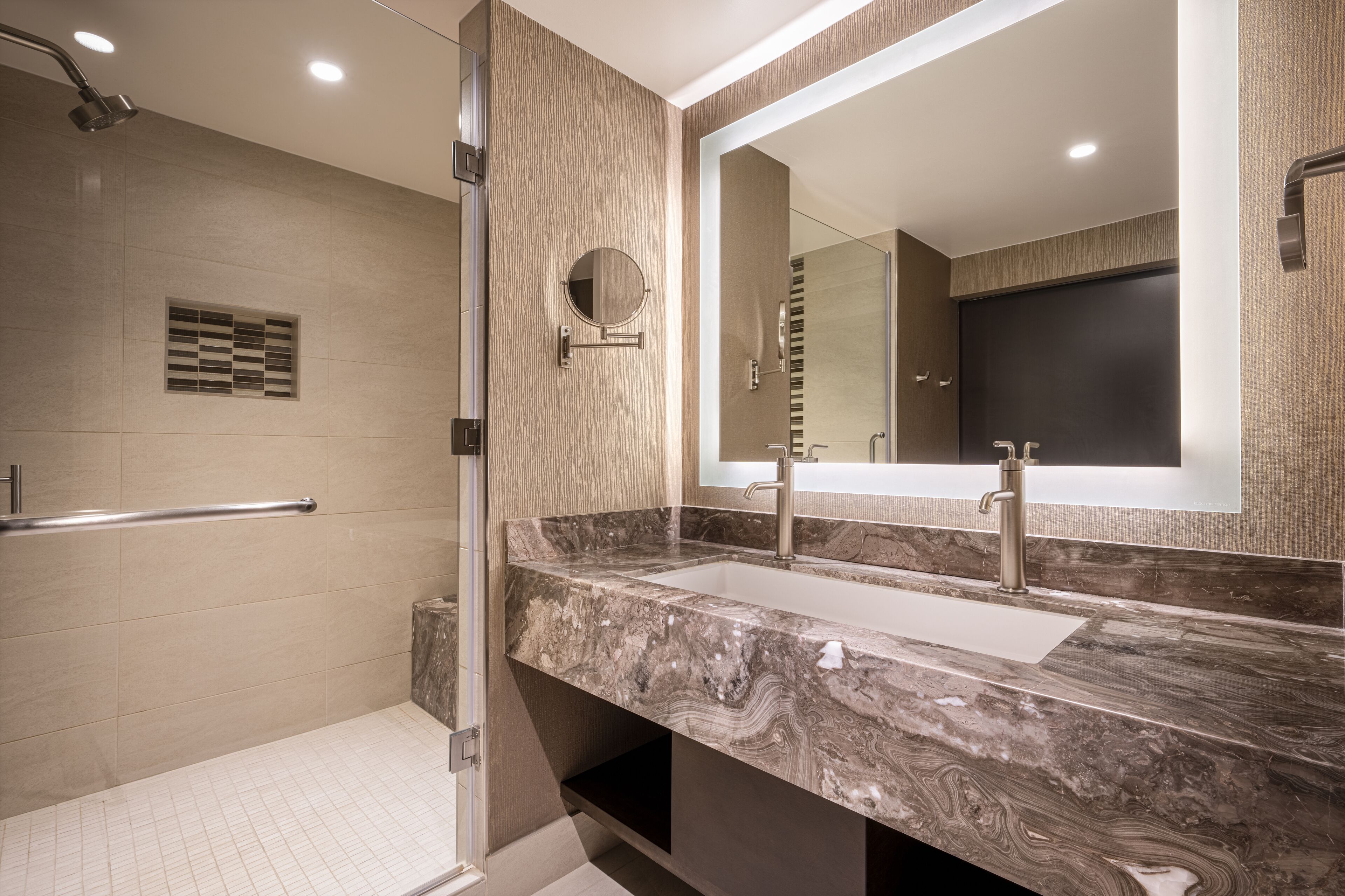 Une salle de bain moderne avec un grand miroir, deux lavabos et un espace douche.