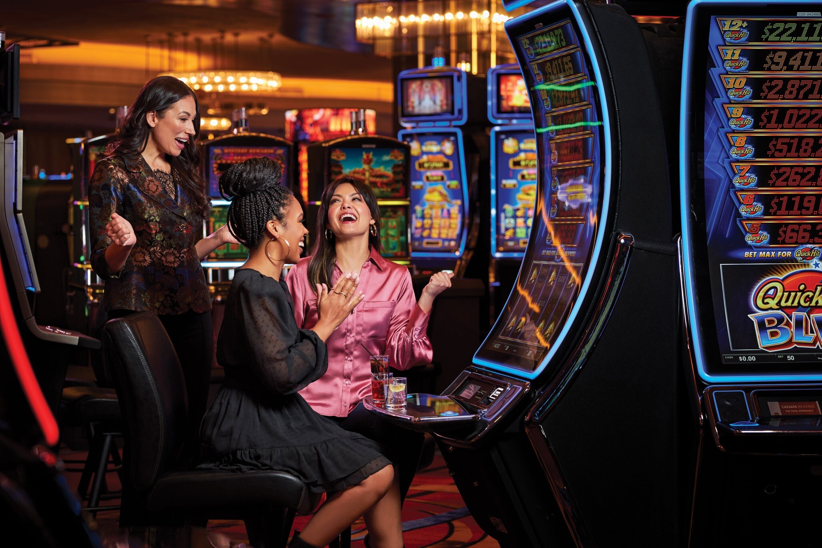 Un casino avec des machines à sous, et une femme portant un chemisier rose qui y joue.