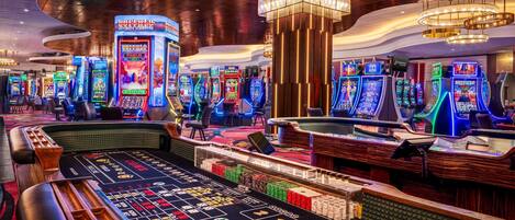 A casino floor with multiple slot machines, a roulette table, and a blackjack table.