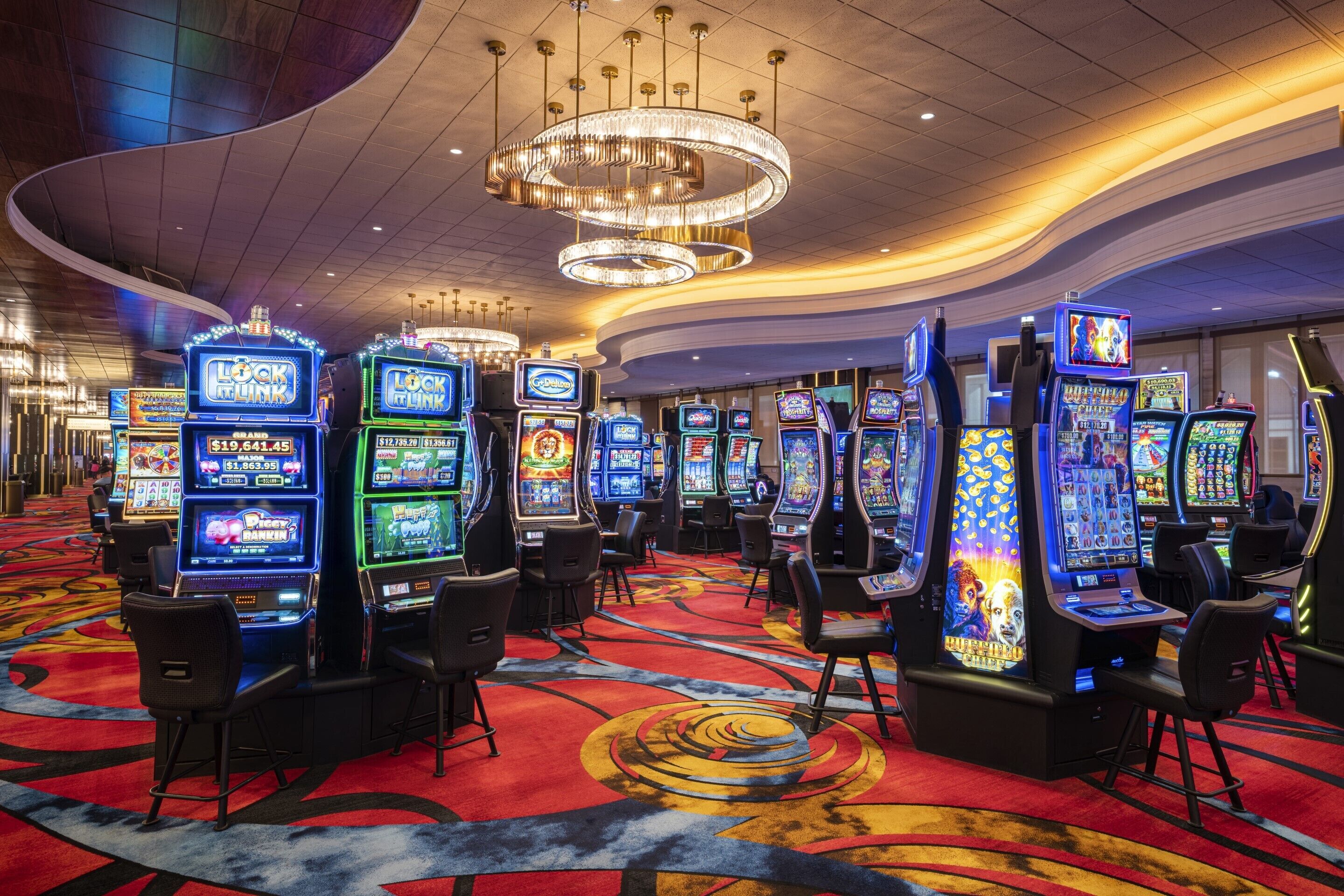 A casino with multiple slot machines and a red carpeted floor.