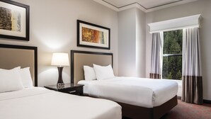 A hotel room with two beds, a nightstand with a lamp, framed artwork on the walls, and a window with curtains. - Lady Luck Casino Black Hawk - A Caesars Rewards Destination (Black Hawk)