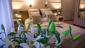 Une chambre d’hôtel avec un lit bien fait, une table de chevet avec une lampe et un grand miroir au mur.