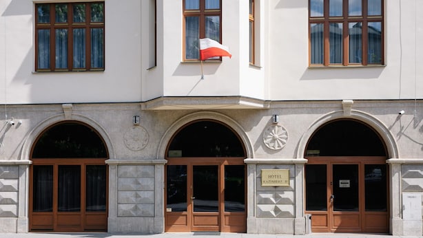 Un bâtiment sur lequel on peut lire l’inscription « HÔTEL KAZIMIERZ II » et où flotte un drapeau au deuxième étage.
