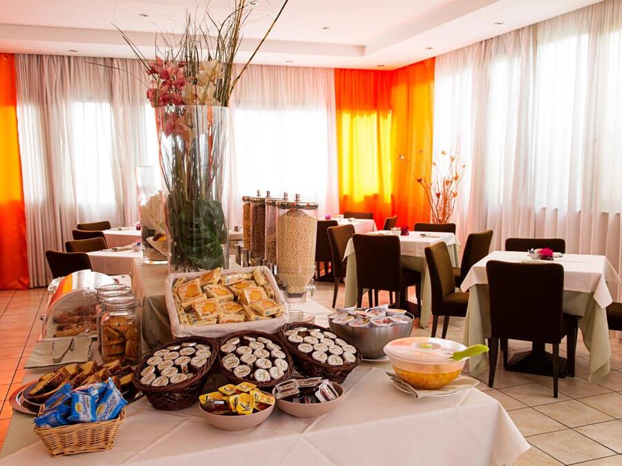 A dining area with tables set for a meal, surrounded by various food items and a decorative vase.