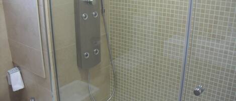Un baño moderno con ducha de vidrio, un lavabo blanco y paredes con azulejos.