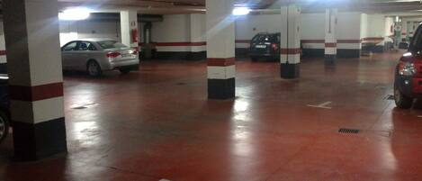 A multi-level parking garage with white pillars and red flooring.