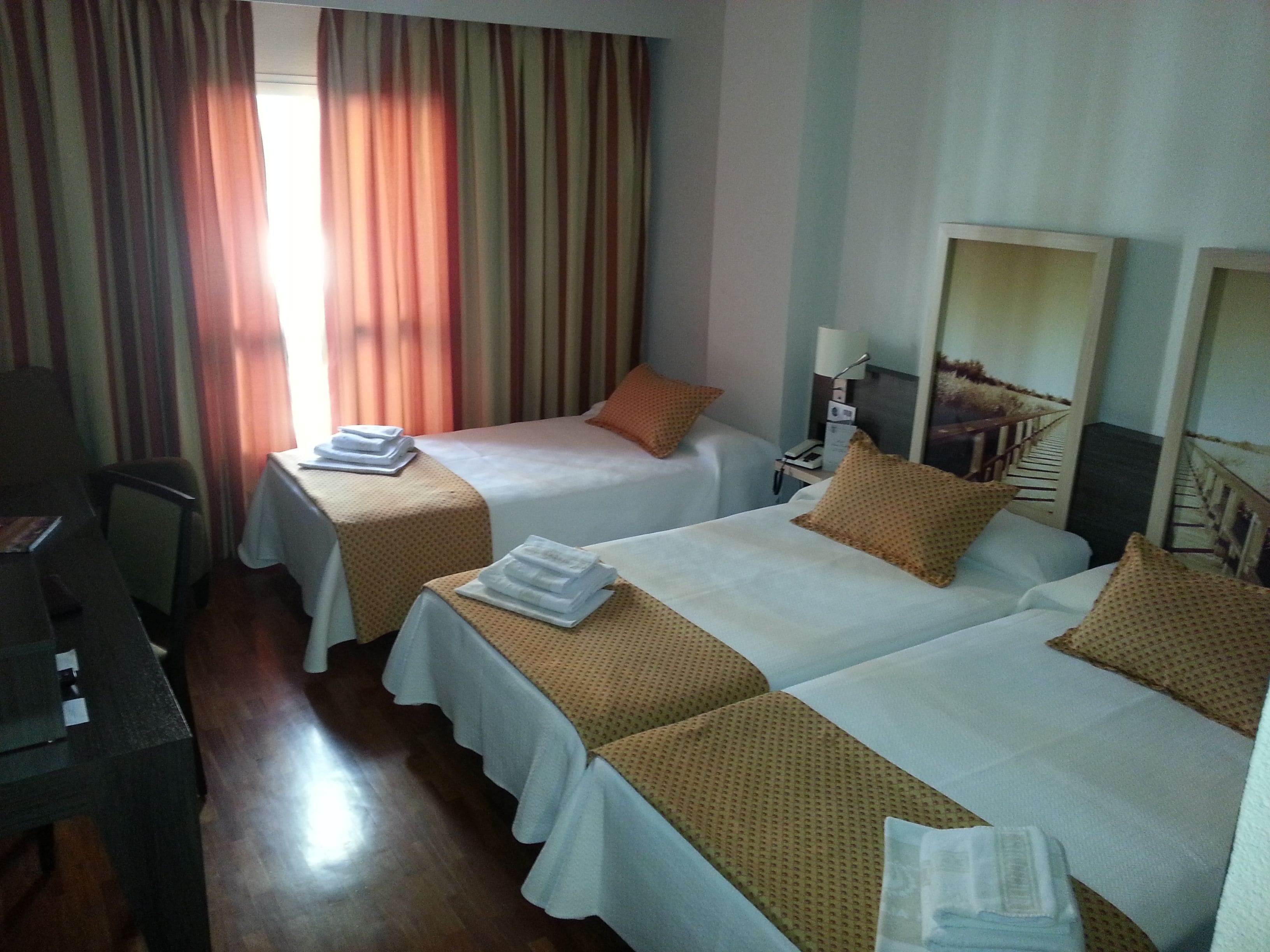 A hotel room with two beds, a desk, and a chair.